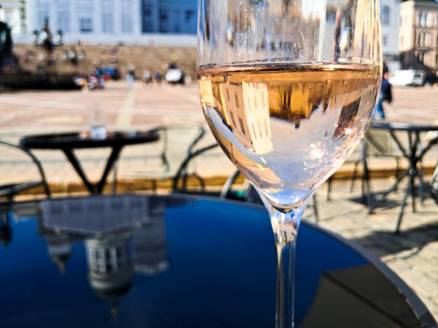 Senaatintori, terävyys lasin pinnassa. Lasista heijastuu tori väärinpäin, pöydästä heijastuu kirkko.