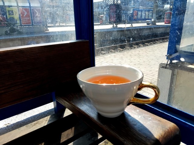 Pasilan asema ja valkoinen kullattu kuppi, missä on teetä.