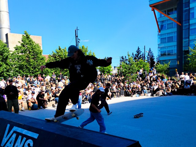 Taustalla katsomo, edessä skeittareita tekemässä temppuja