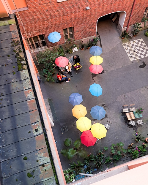 Kuvassa sisäpihalla on erivärisiä varjoja ja joitain ihmisiä. Kuva on otettu ylhäältä alaspäin.